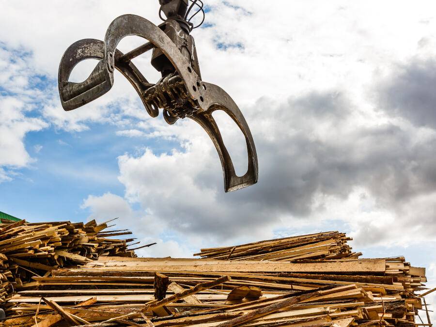 Grab lorry claw above piles of wood waste