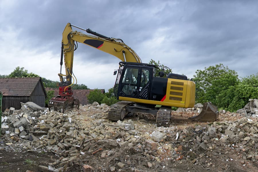 Large yellow excavator removing rubble